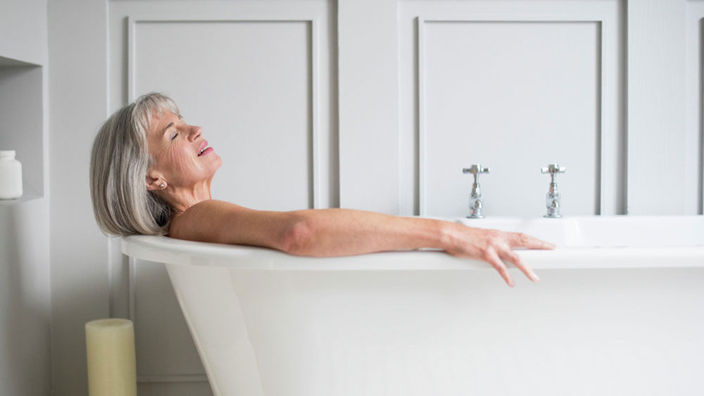 Uma mulher de meia idade está deitada na banheira