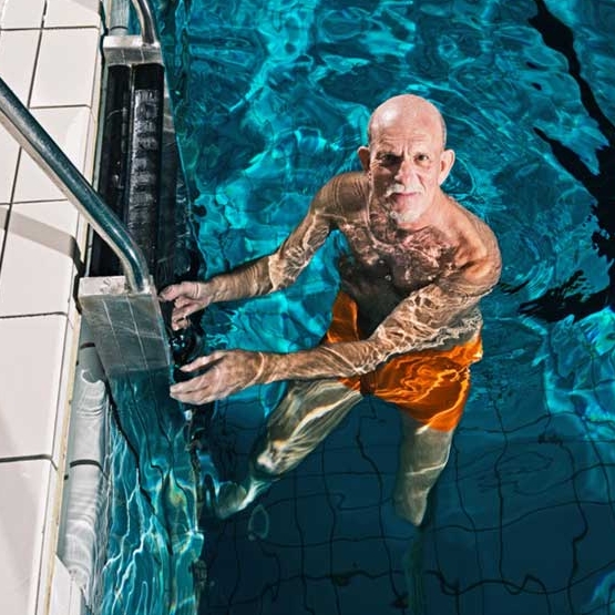homem idoso numa escada numa piscina