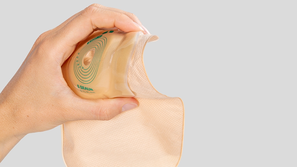 Mão a segurar num saco de ostomia convexo