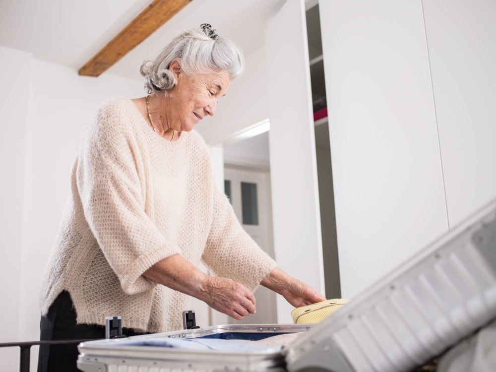 Uma mulher idosa faz a mala e sorri