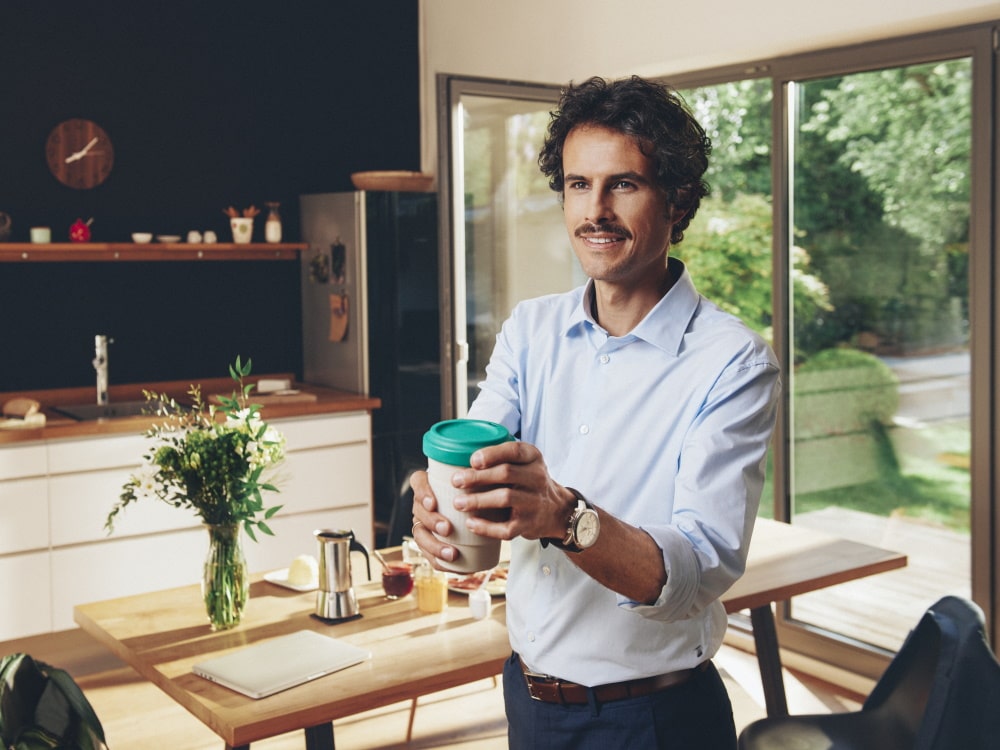 Um homem está numa casa privada a segurar numa chávena de café