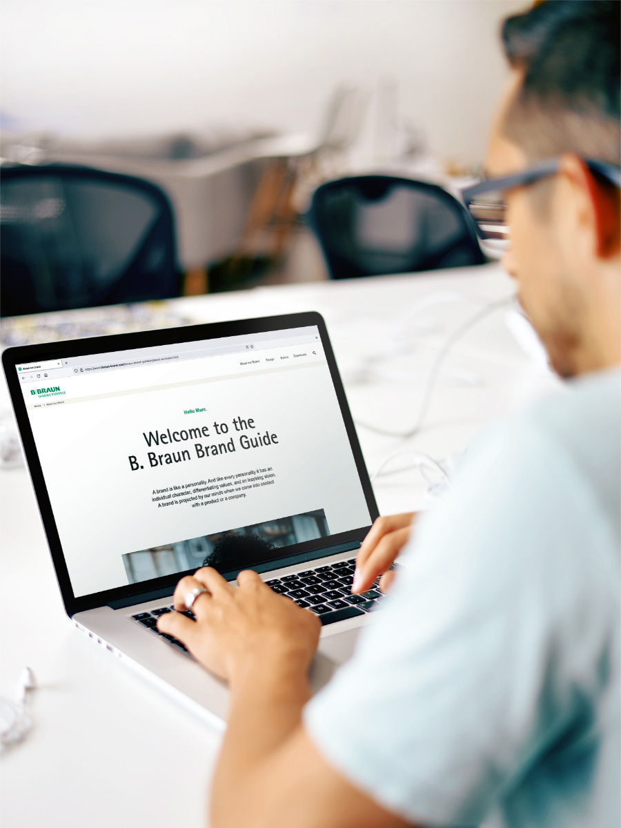 Um homem com uma camisa azul claro a operar um computador portátil com o site da B. Braun aberto.