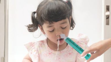 Uma criança a fazer a lavagem nasal com uma seringa da B. Braun